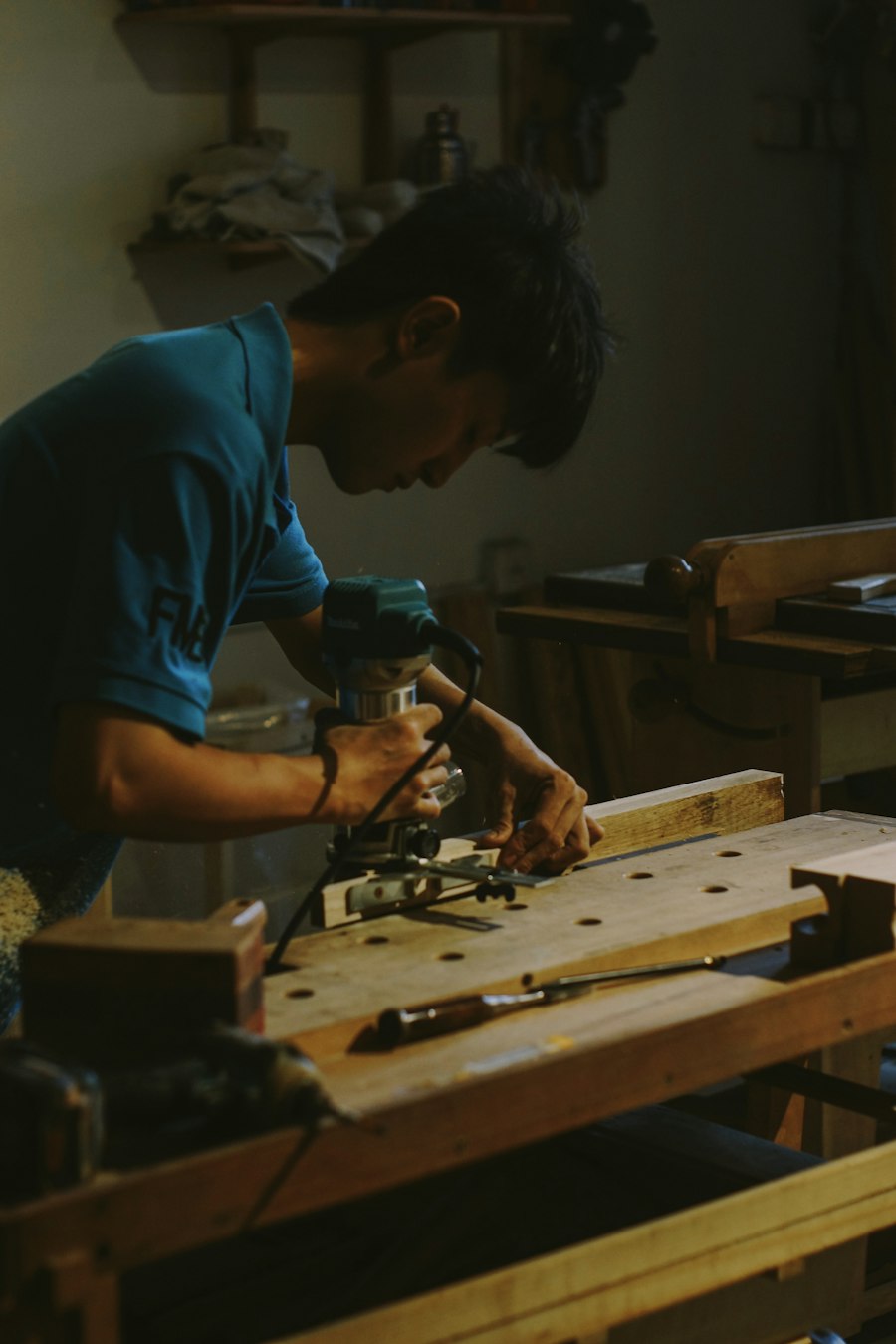 A woodworker guiding a router along a board in a workshop; illustrative craftsmanship